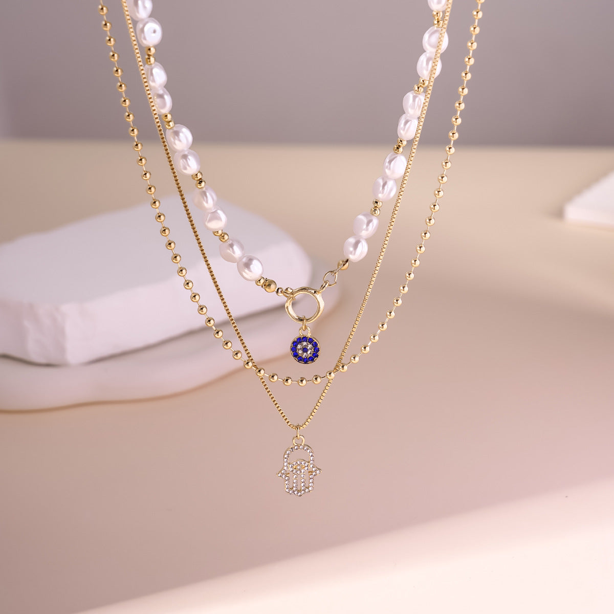 Elegant Layered Pearl Necklace with Evil Eye & Hamsa Charm – Chic and Protective