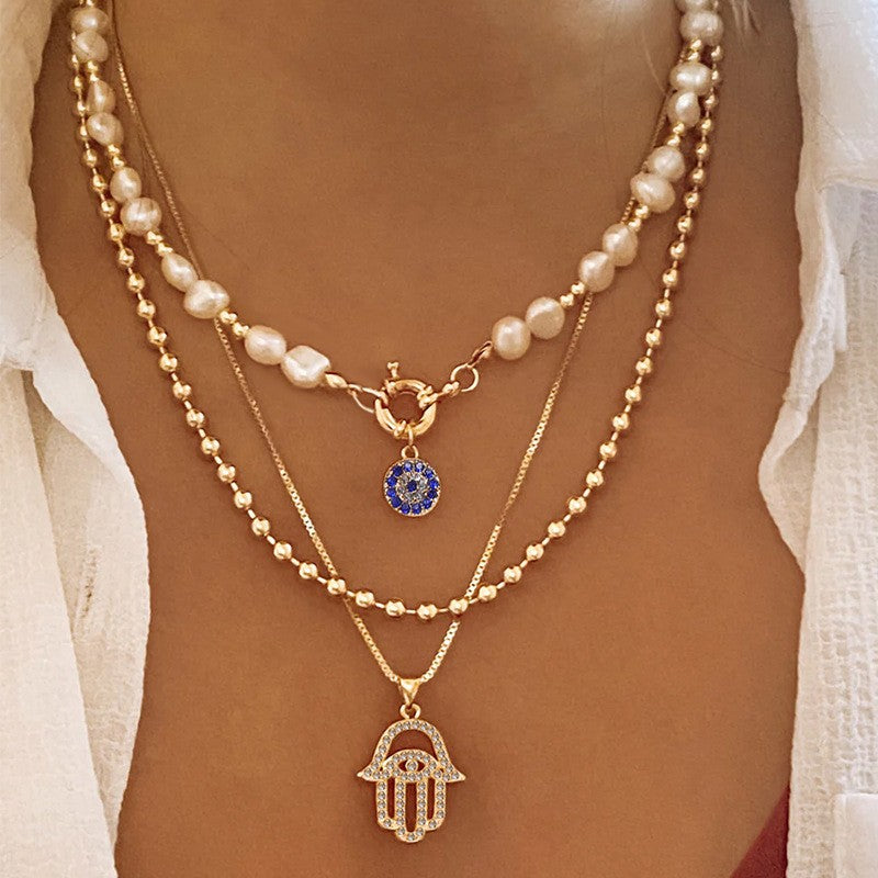 Elegant Layered Pearl Necklace with Evil Eye & Hamsa Charm – Chic and Protective